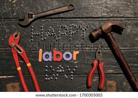 Happy Labor day text in red color on wooden background with construction repair tools. Labor day concept sign. Happy labor day - writing screws.