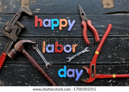 Happy Labor day text in red color on wooden background with construction repair tools. Labor day concept sign. Happy labor day - writing screws.