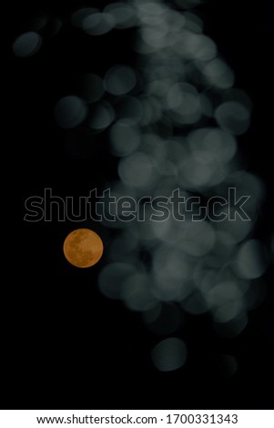 Full moon with translucent white bokeh in black background.