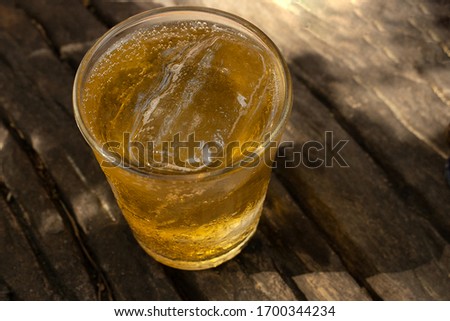 Beer and ice in a glass placed on a wooden floor