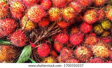 full frame shoot of bunch of red rambutan fruits at traditional market