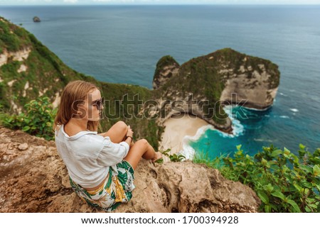 girl looks at Kelingking Beach on Nusa Penida, Bali, Indonesia.