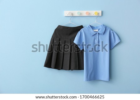 Stylish school uniform hanging on color wall Royalty-Free Stock Photo #1700466625