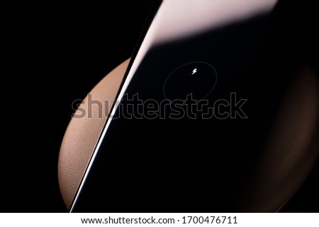 Smartphone Screen over Wireless Charger Showing a Charging Battery Sign. Copy Space.