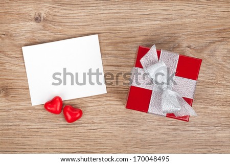 Blank valentines greeting card and small red gift box on wooden background