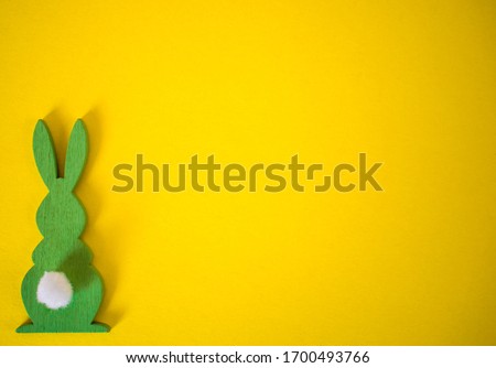 Green Easter bunny on yellow background. Easter holidays yellow background