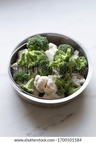 Broccoli and cauliflower on white marble background
