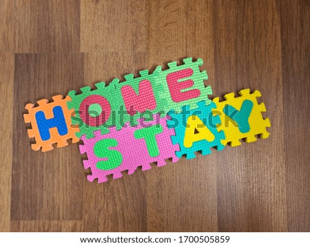 Colorful alphabet letters form the expression "Home Stay" in a wooden  background