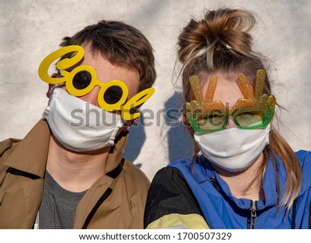 Two teenagers, a young man and a girl, in protective medical masks and funny glasses. Support during the covid-2019 coronavirus epidemic.