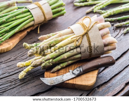 Green and white types of asparagus sprouts on wooden table. Top view. Royalty-Free Stock Photo #1700532673