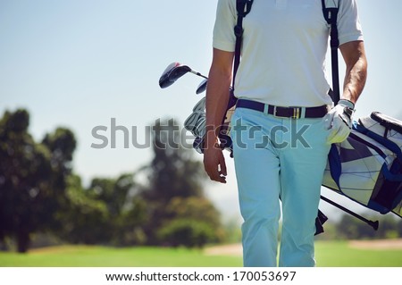 Golf player walking and carrying bag on course during summer game golfing Royalty-Free Stock Photo #170053697