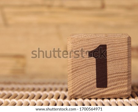 Wooden cube with the number one on a beige background.
