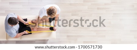Physiotherapist Giving Band Resistance Exercise Therapy Treatment  Royalty-Free Stock Photo #1700571730