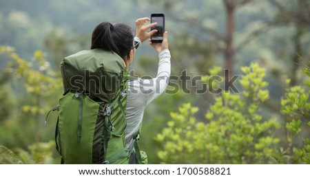 Woman hiker using smartphone taking pictures in spring mountain 