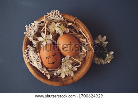 Pair of easter brown eggs in a wooden bowl on a blue background top view