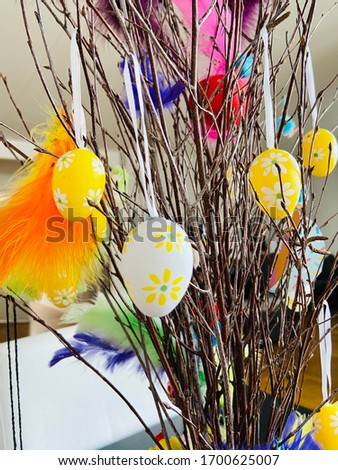 A close-up of colorful Easter eggs and Easter chicks hanging in Easter branches.