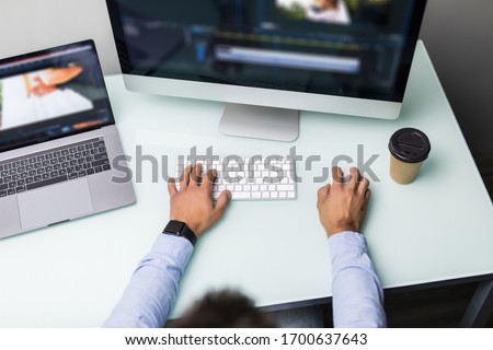 Low angle view of young man video editor with works with footage on his personal computer with big display in office