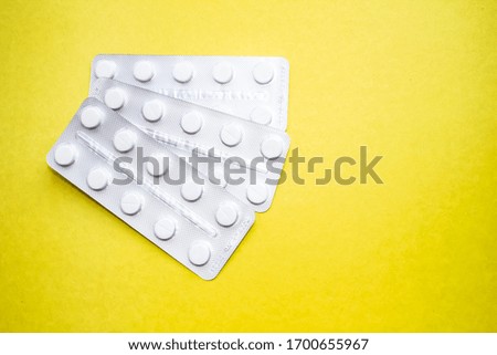 Medical pills in plastic packaging on a yellow background