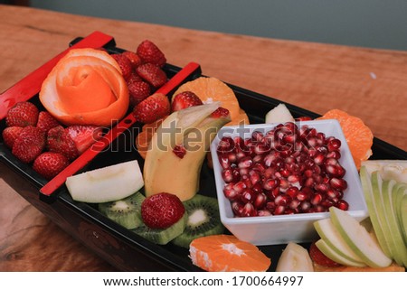A tasty delicious fruits on white plate, banana, pomegranate, mandarin, apple, orange, pear