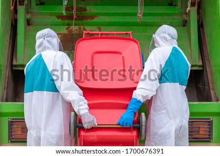 worker wear PPE protective clothing against corona virus of Infectious waste garbage collector truck loading waste and trash bin. Royalty-Free Stock Photo #1700676391