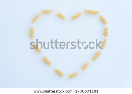 Top view of italian pasta in a heart shape, fusilli isolated on white background.