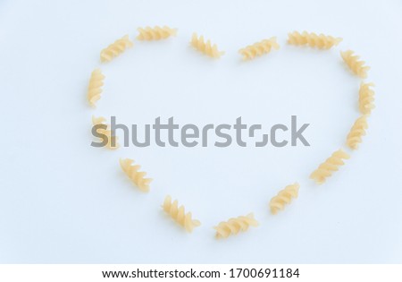 Italian pasta in a heart shape close up, fusilli isolated on white background.