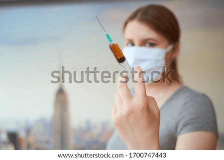 girl in a protective mask with a syringe in her hand in New York