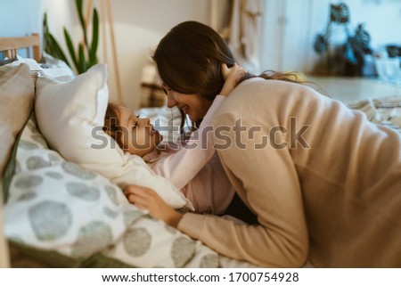 daughter hugs mom lying on the bed. the child missed her mom. school students at quarantine at home