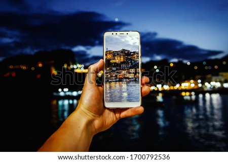 Using your smartphone as a mobile camera while traveling. Tourist city at dusk on screen