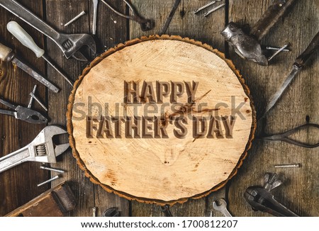Happy Father's Day. Congratulatory text on an old rustic wooden background surrounded by various tools in the workshop.workers day.A greeting card or banner for your store or website.FLat lay.Top view