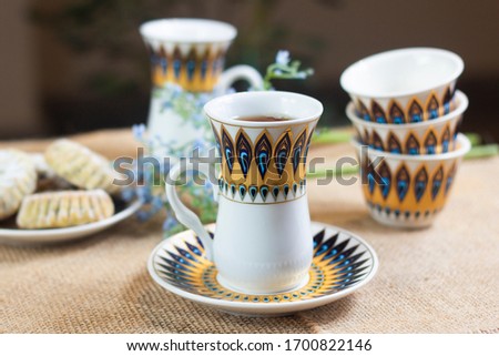 a set of decorated glass tea cups with some arabic turkish sweets 