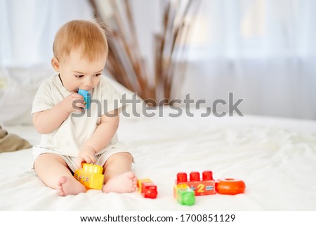 Toddler baby playing with toys, tastes them. Royalty-Free Stock Photo #1700851129