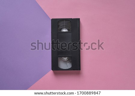 Top view of Large picture of an old Video Cassette tape on a pink and purple background . Minimalistic retro concept