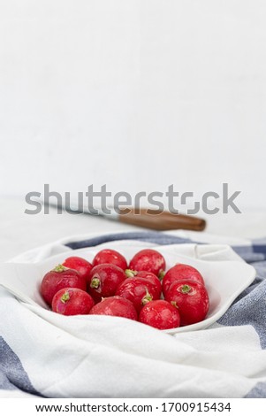 Fresh red radishes on the bowl with knife on the table