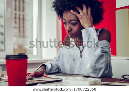 Having depression. Cute international girl sitting at her workplace while looking for new ideas