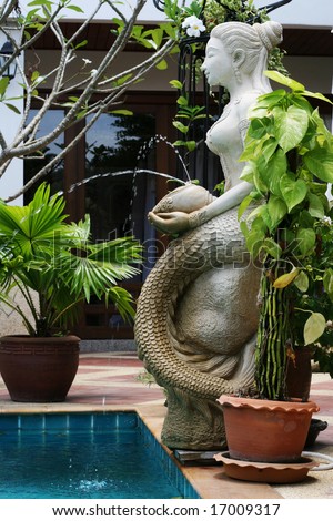 Mermaid statue at the side of a swimming pool.