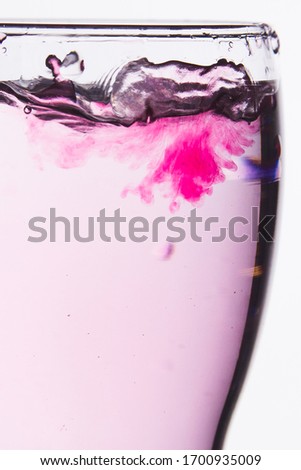 Glass with water on white background with soluble in red rose dissolving