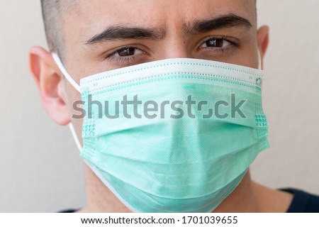 portrait of brunette man in a surgical bandage on a background of a wall, coronavirus, illness, infection, quarantine, medical mask