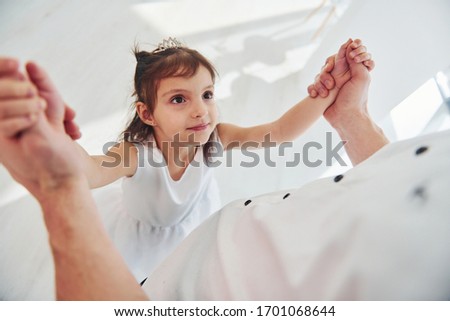 Happy father with his daughter in dress learning how to dance at home together.