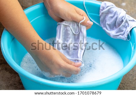 Washing a mask using detergent dissolved in water. Washing the masks is disinfecting and saving money to be used again.