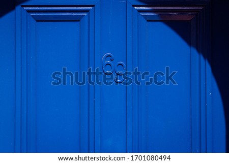 House number 69 in blue on a blue wooden front door