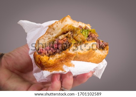 
hand holding bitten burger on gray background