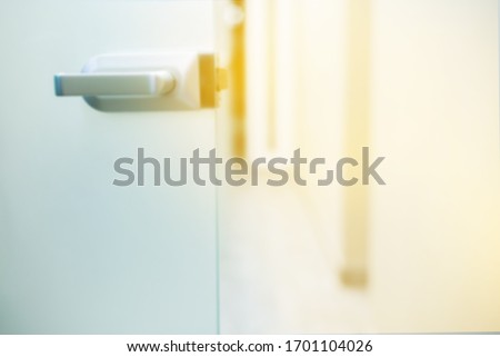 
glass door in an open ward of a clinic against a white wall. space in the hospital with a glass door and a metal handle. fight against Covid -19. image as background