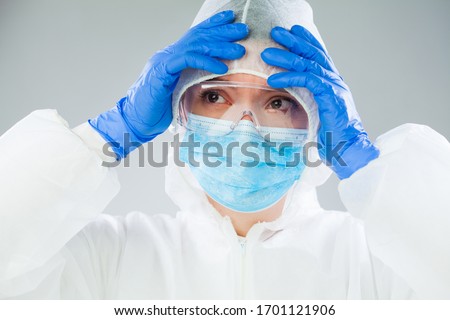 Desperate NHS UK medical EMS worker in white protective suit,blue surgical mask latex gloves safety goggles,Coronavirus COVID-19 pandemic crisis causing protective personal equipment supply shortage Royalty-Free Stock Photo #1701121906