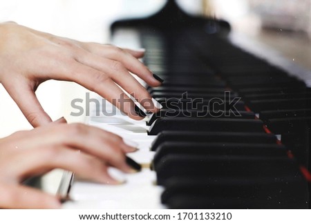 Monochrome black and white manicure nails on piano keys, female graceful hands playing music close up Royalty-Free Stock Photo #1701133210