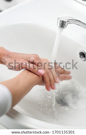 Woman use soap and washing hands under the water tap. Cleaning Hands. Hygiene. Pink manicure. Soft focus