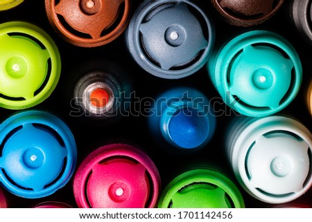 Macro image of a set of Artist's colored markers in a cup closely grouped with the caps facing up with one turquoise broad tip and one pink fine tip marker uncapped in the center as an OCD trigger