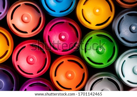 Macro image of a set of Artist's colored markers in a cup closely grouped with the caps facing up.  Bright colors and sharp focus.