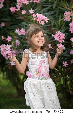 A girl in a white dress with a unicorn on the background of flowering trees