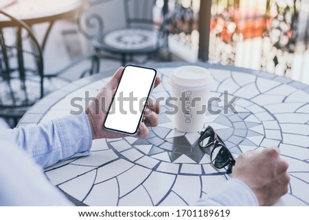 cell phone Mockup image blank white screen.man hand holding texting using mobile on desk at coffee shop.background empty space for advertise text.people contact marketing business,technology 